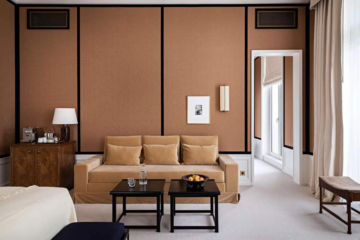 A bedroom with tan paneling, a bench at the foot of the bed, and wood accents