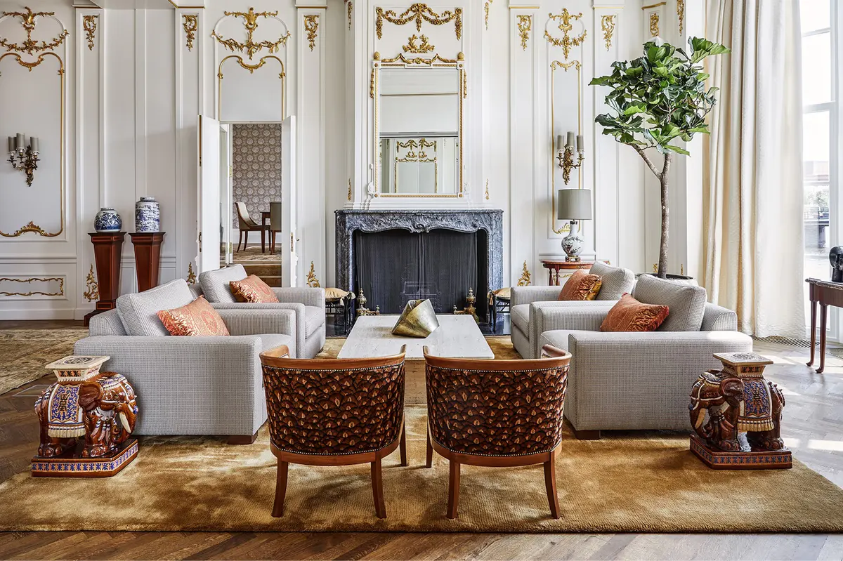 Living room with cream seating, fireplace, arched windows, and classical proportions
