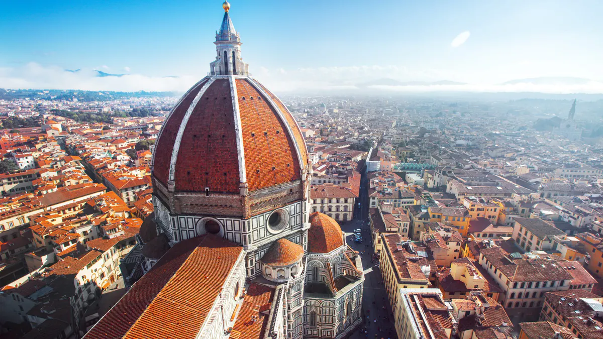 Aerial view of Florence cathedral dome rising above the dense terracotta-tiled cityscape