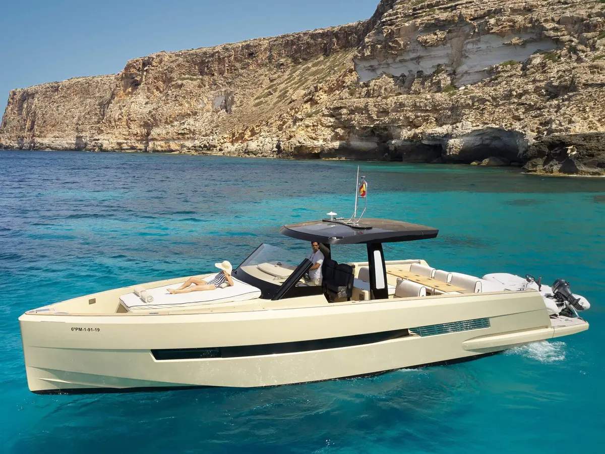 A motorboat in crystal turquoise waters framed by limestone cliffs at Cala Blava