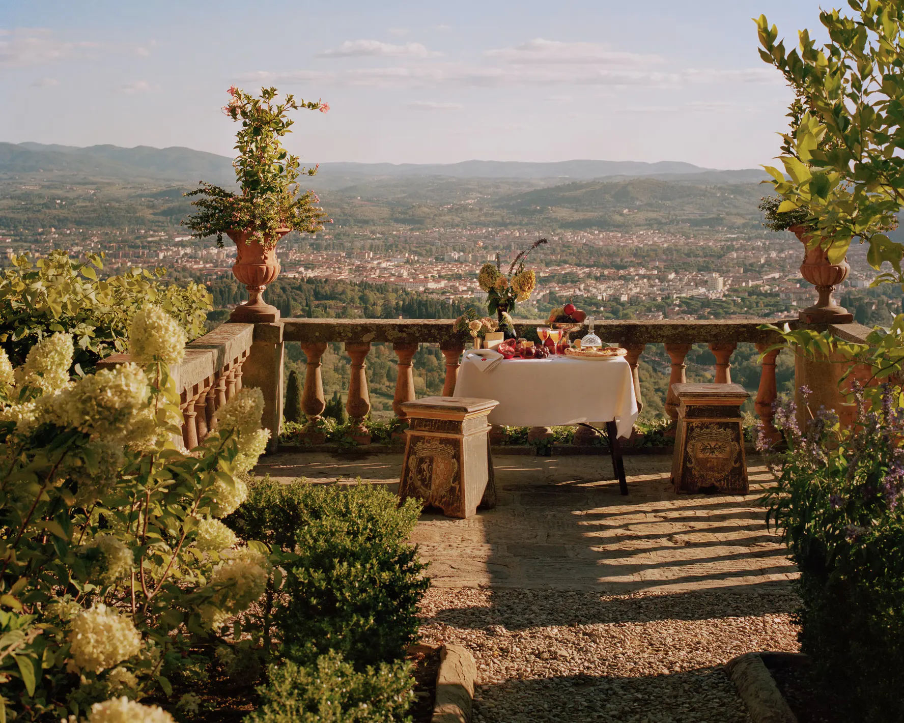 A table laid for lunch on a balustraded terrace, with Florence spread across the valley behind it