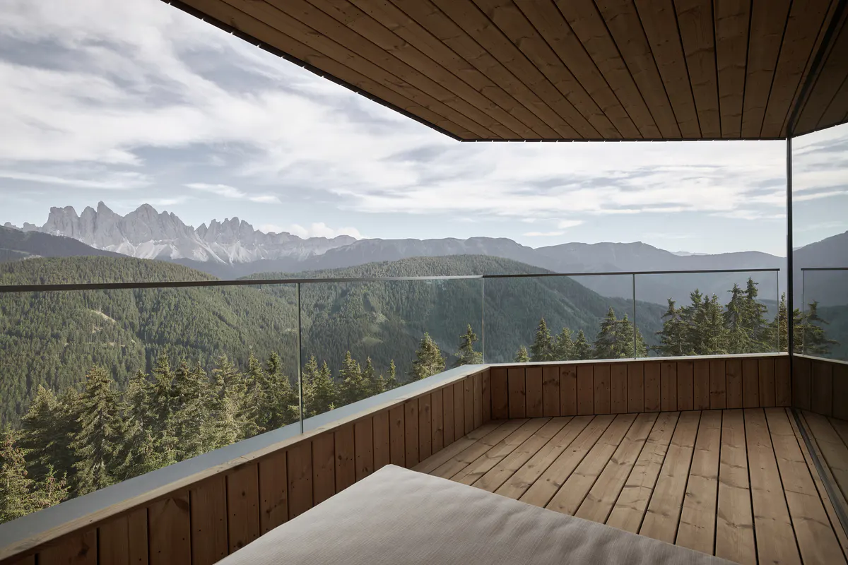 A modern guest suite with neutral decor, warm wood floors, and large windows framing landscape views