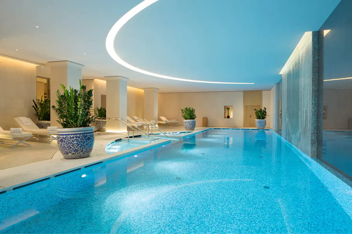 Modern bathroom entrance with glass doors opening to a spa pool with blue water