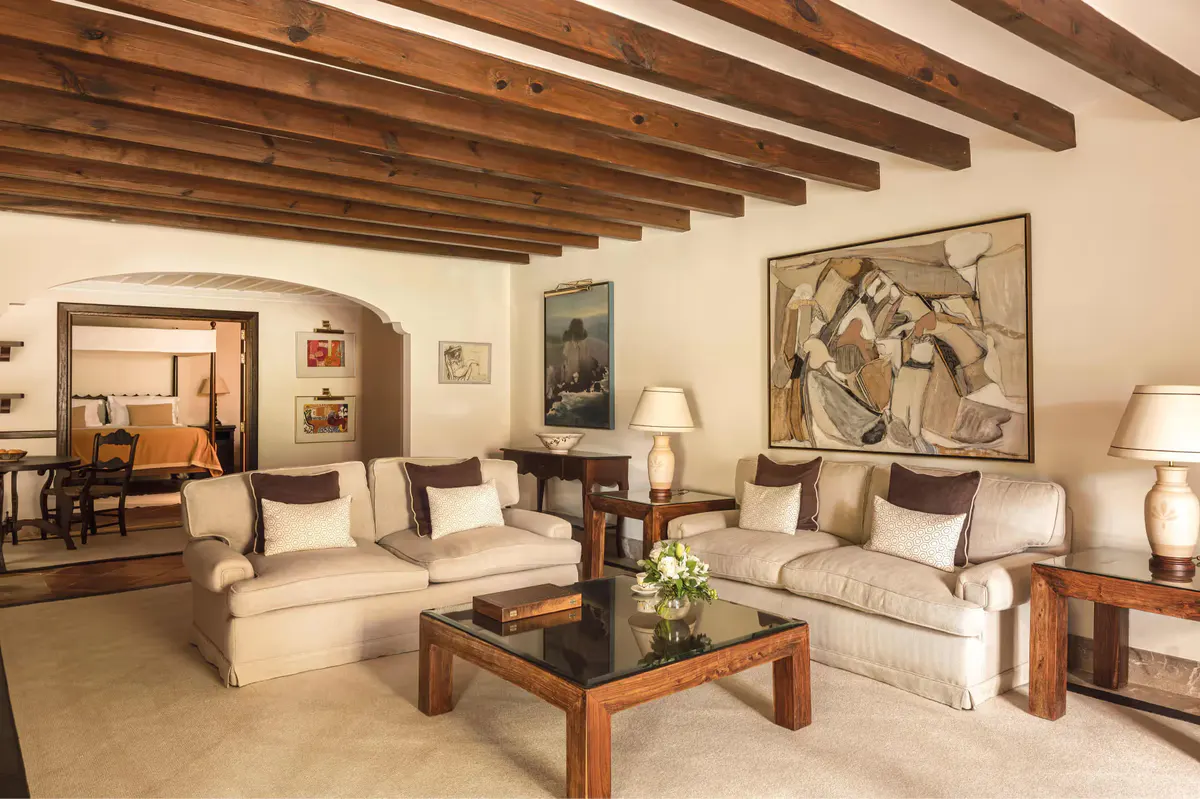 Living room suite with beamed ceiling, sectional sofa, coffee table, and terracotta tile floor