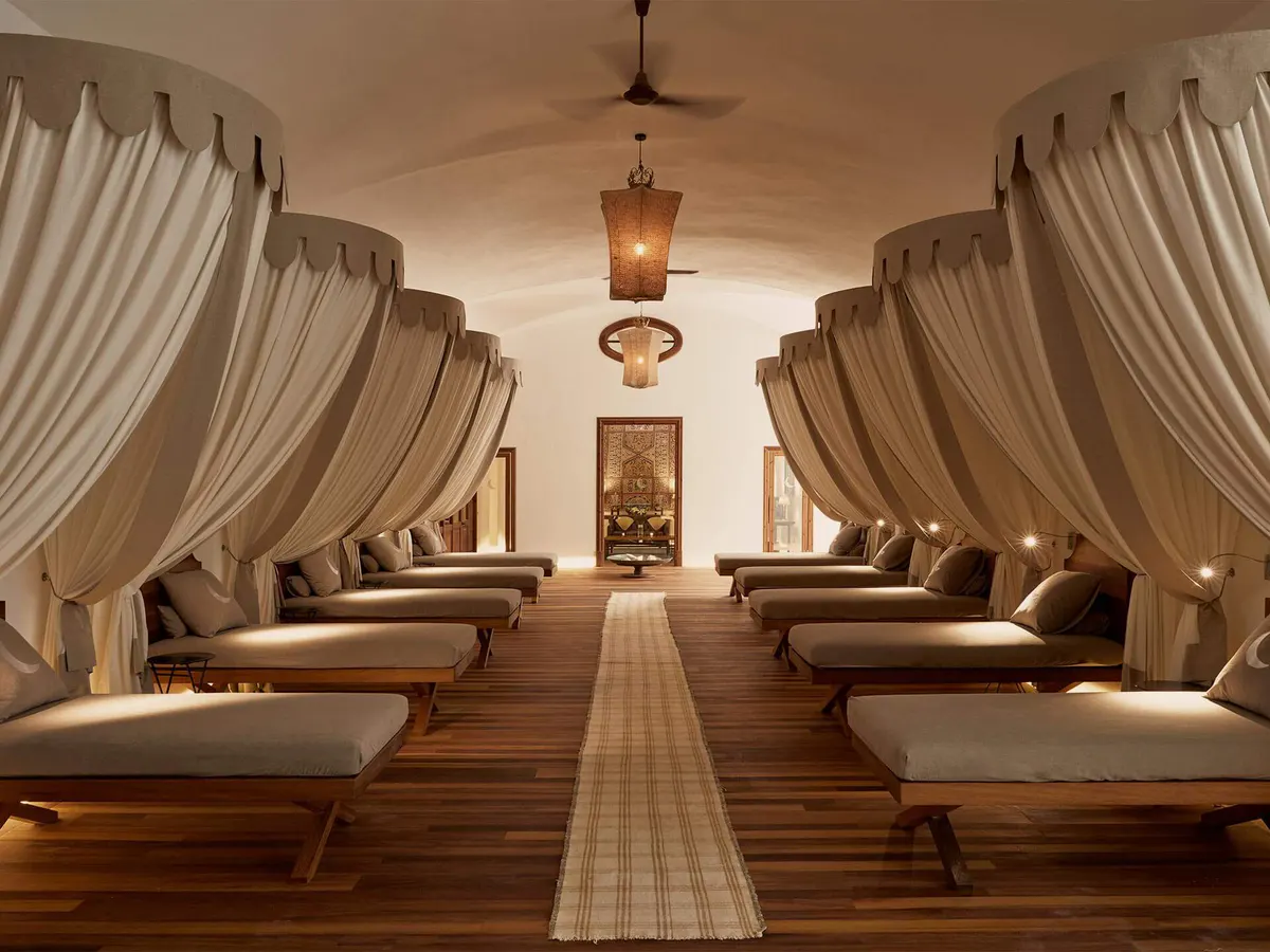 A wellness pavilion lined with cream draped loungers and minimal contemporary furnishings