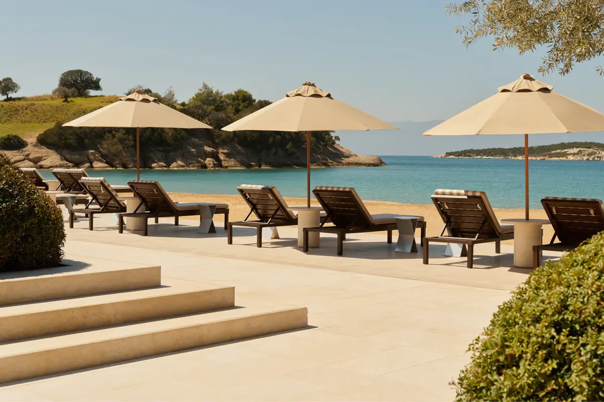 Beach club loungers with umbrellas and calm Mediterranean waters