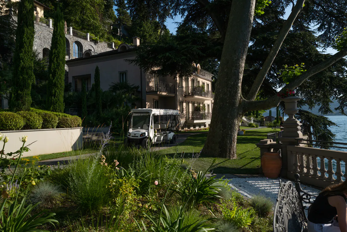Manor grounds with palms, green lawn, stone structures, and terraced architecture