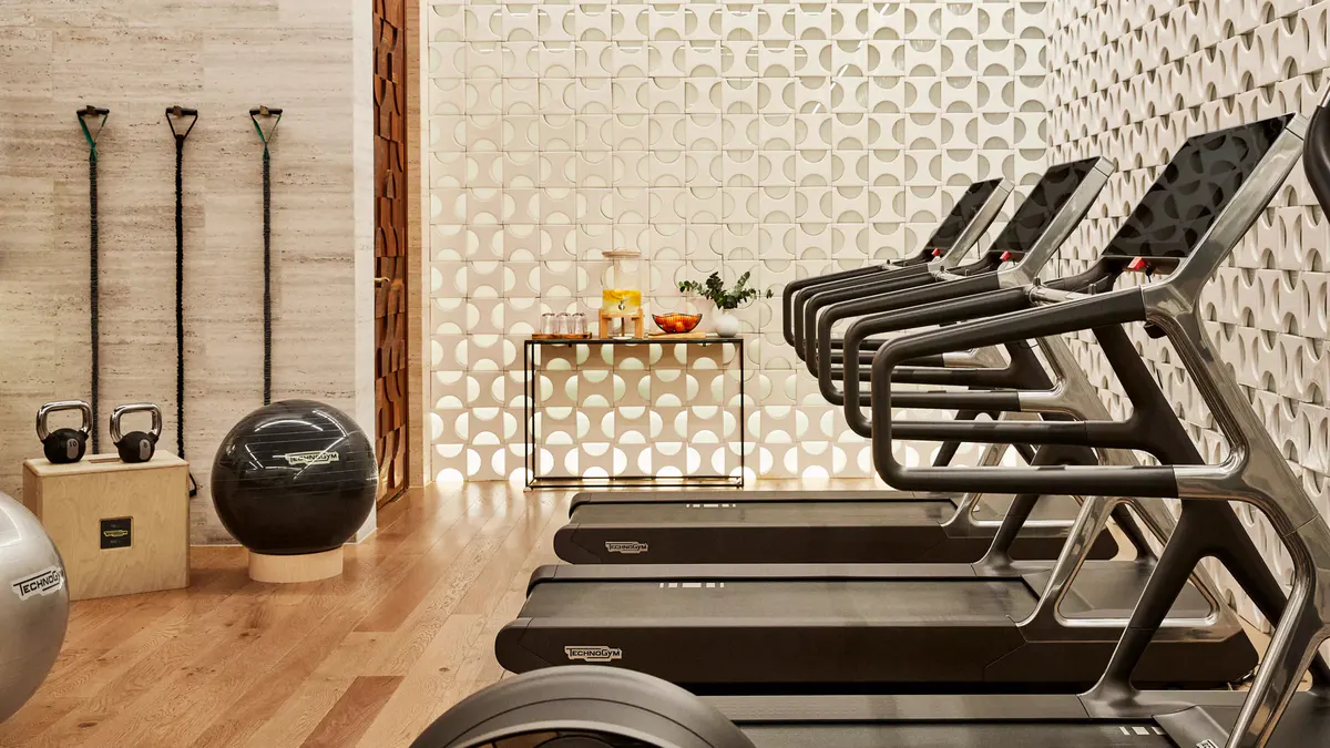 A fitness center with treadmills, geometric tile flooring, and minimalist design
