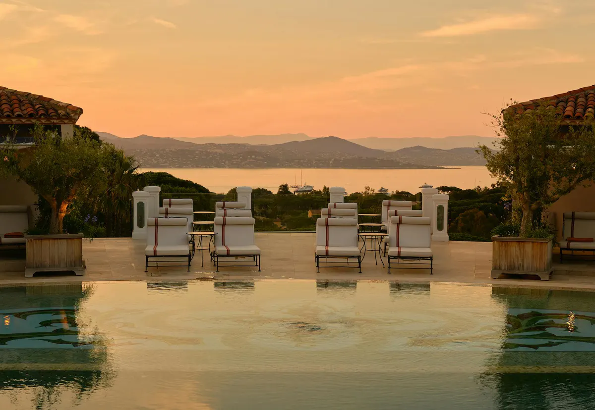Sunset view with lounge chairs arranged by the pool at dusk