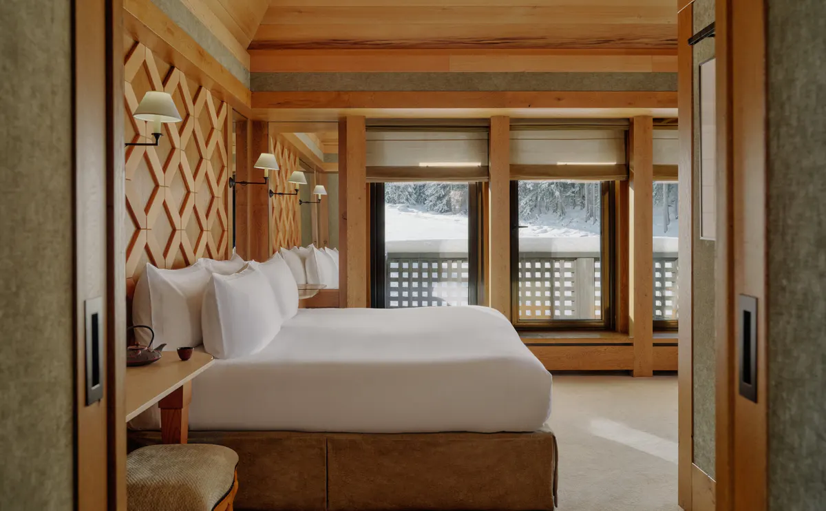 Bedroom with a diamond lattice wood wall and glass doors opening onto a snow covered balcony