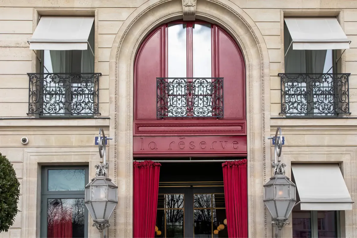The salmon-red arched entrance with brass lanterns on either side