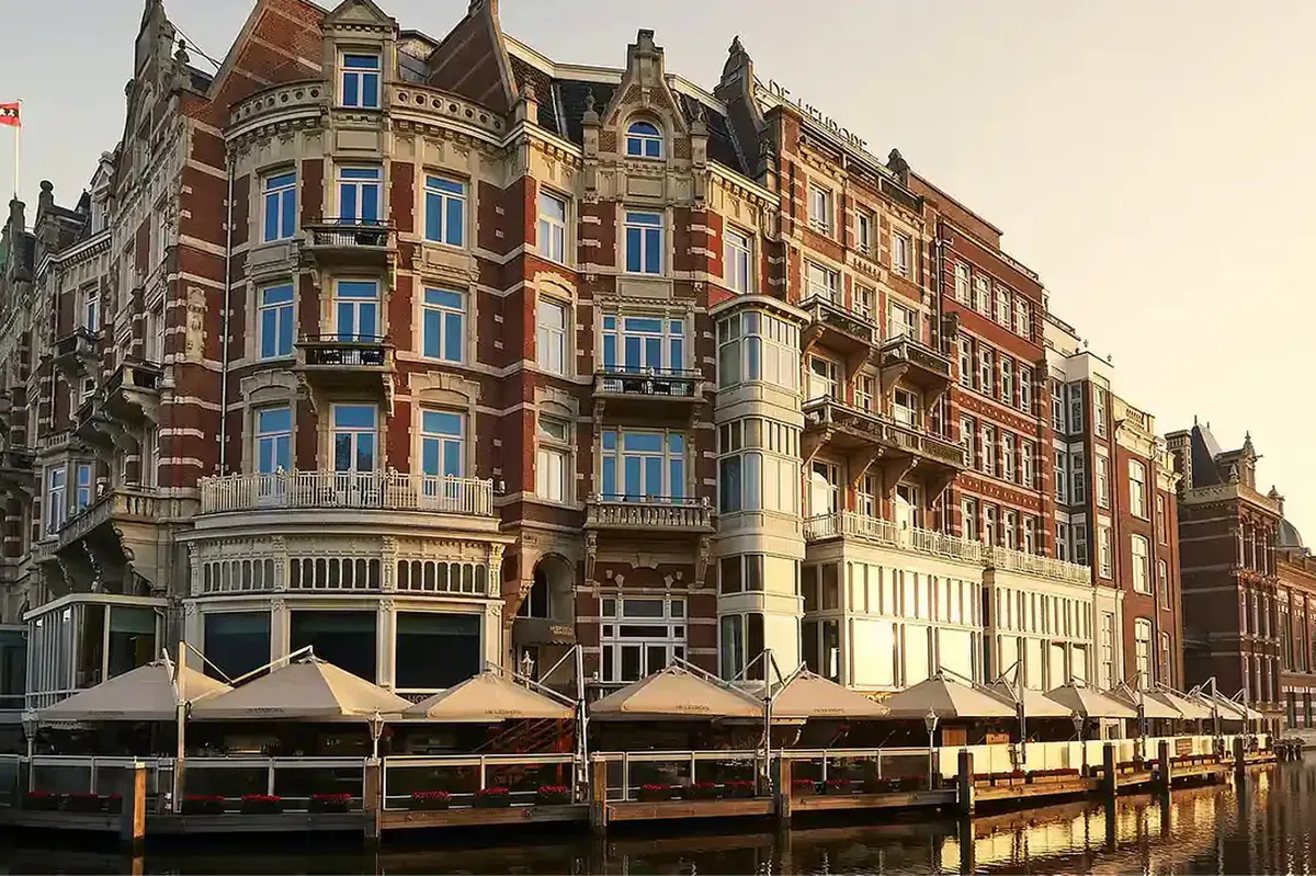 Red-brick historic building facade along the Amstel River with arched windows and decorative stonework