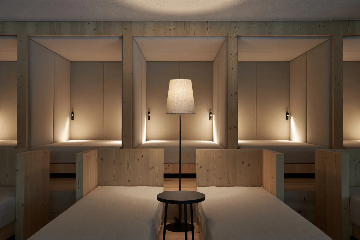 A spa treatment room with a treatment table, wood cabinetry, and soft overhead and side lighting