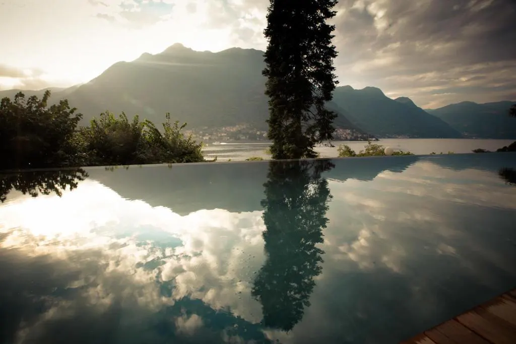 Infinity pool reflecting mountains and clouds at dawn