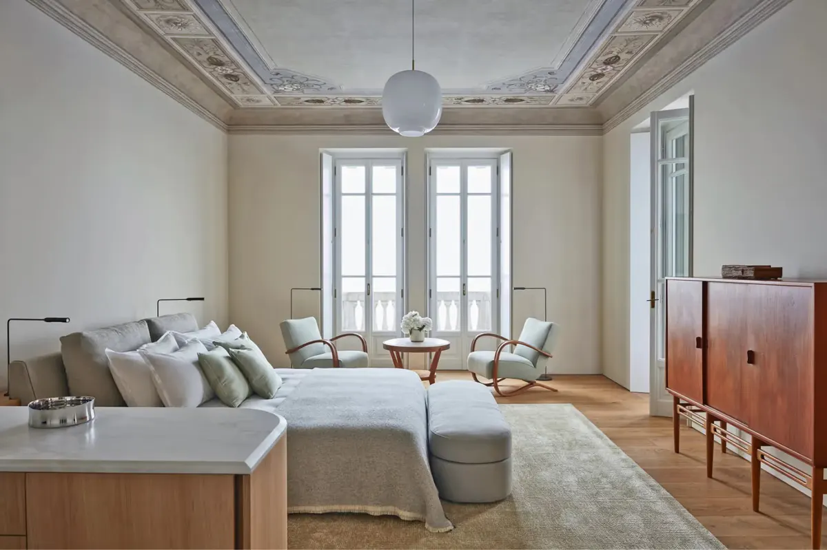 A suite with fresco ceiling detail, white bedding, and French doors to garden
