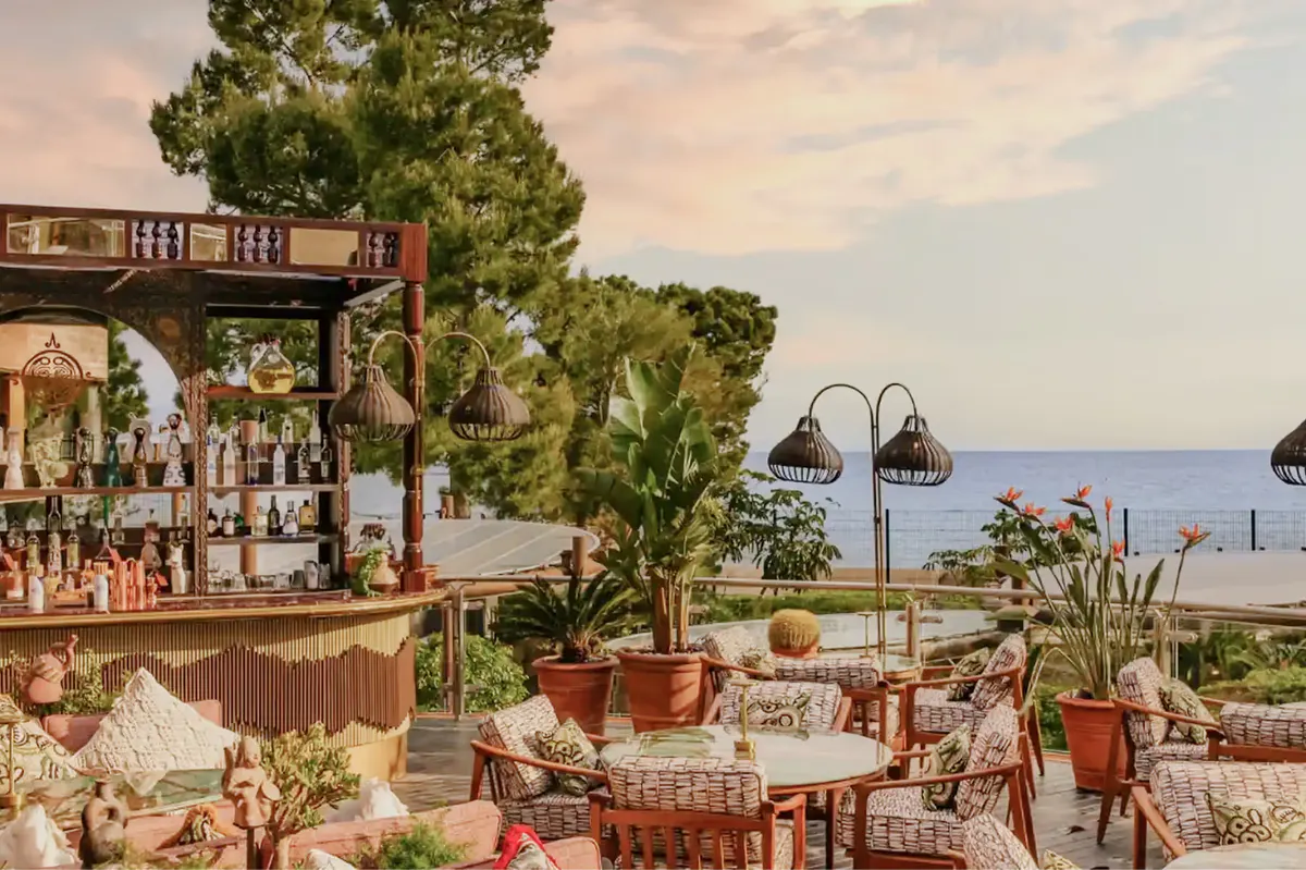 Outdoor terrace restaurant with potted plants and tables facing the sea