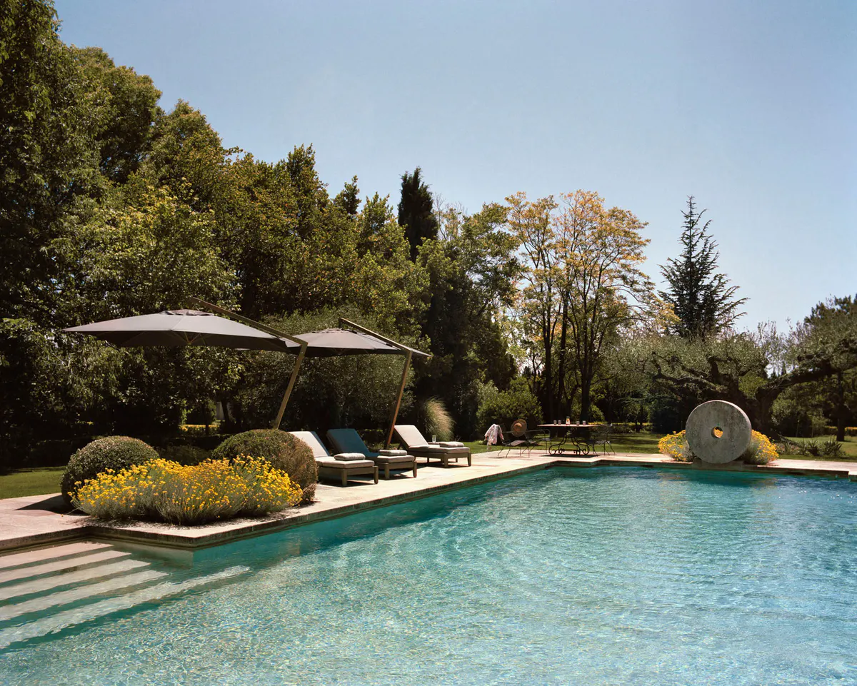 Heated saltwater pool with loungers and umbrellas surrounded by mature landscaping
