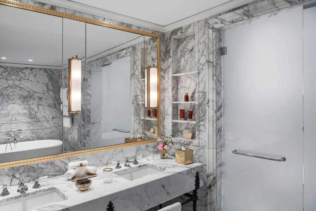 Marble bathroom with brass fixtures, white sink, and framed mirror