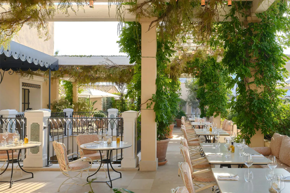 Colonnaded outdoor dining pavilion with ivy climbing the support columns and Mediterranean views