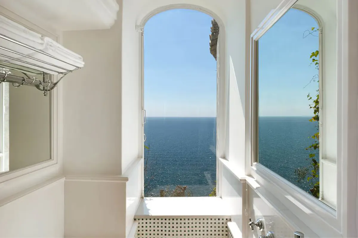 White arched window frames showing Mediterranean sea and sky from bedroom perspective