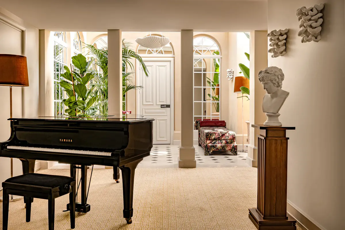 Grand music room with black grand piano, classical columns, and tall French doors