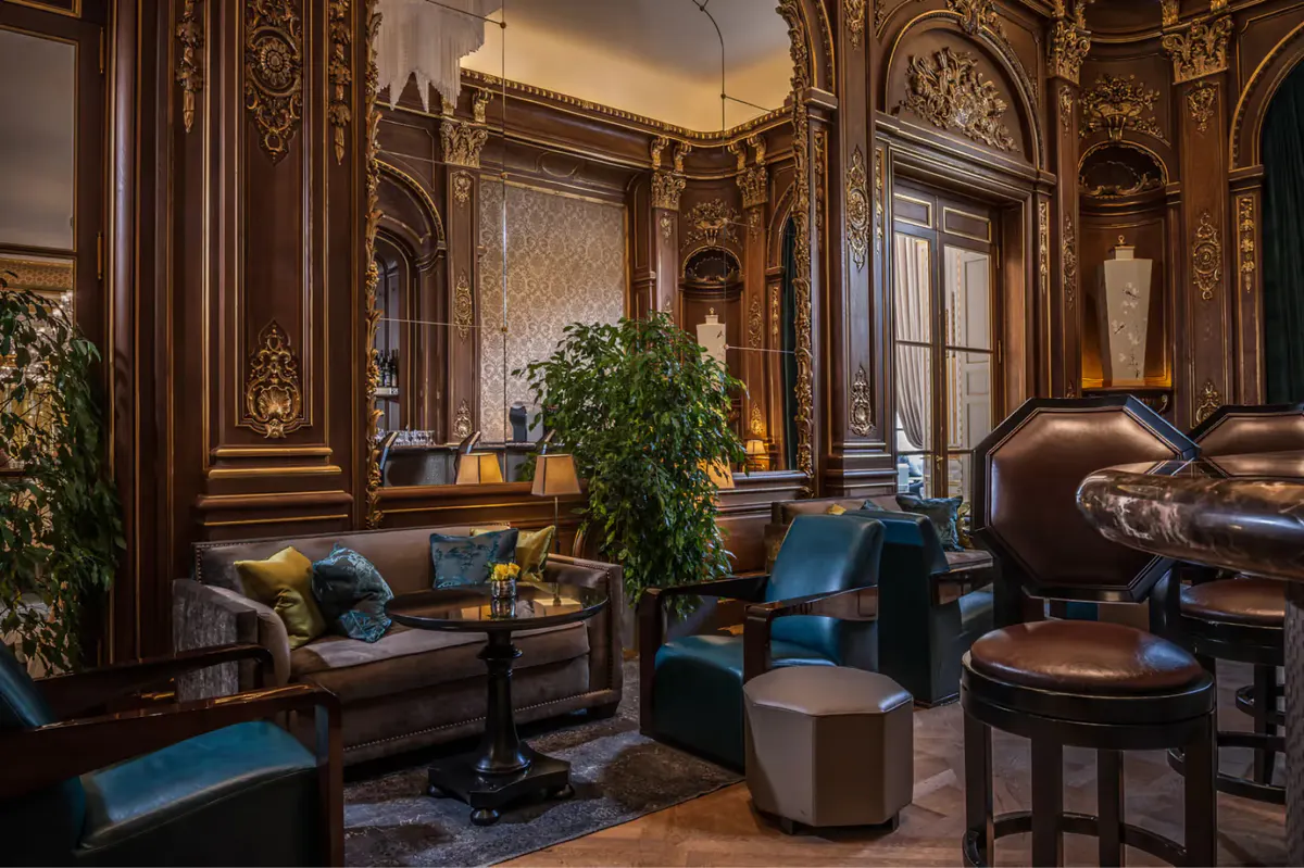 Bar with mirrors reflecting bottles, classical architectural details, and seated guests