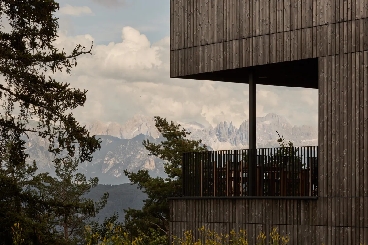 Cantilevered wooden balcony overlooking Dolomite mountain peaks under dramatic sky