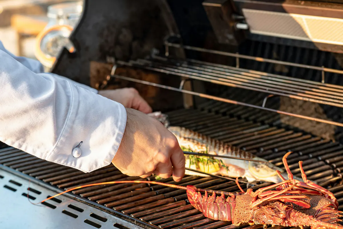 Chef grilling seafood over flames at outdoor station