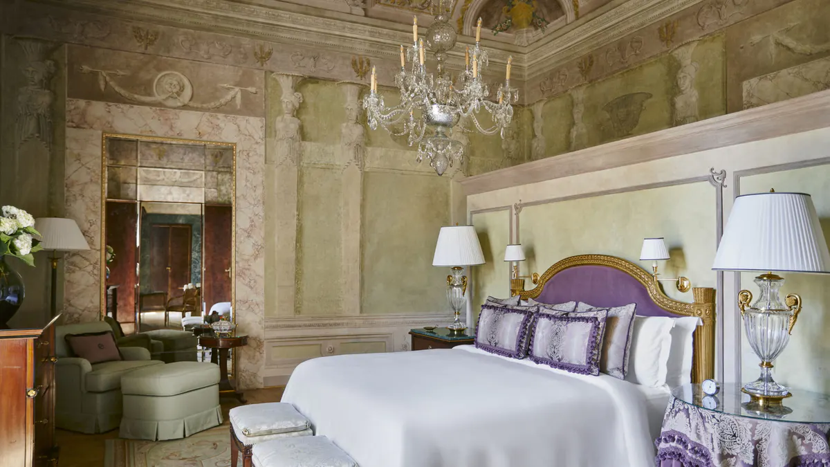 Bedroom with frescoed ceiling, pale green damask walls, and windows with cream and lavender drapery