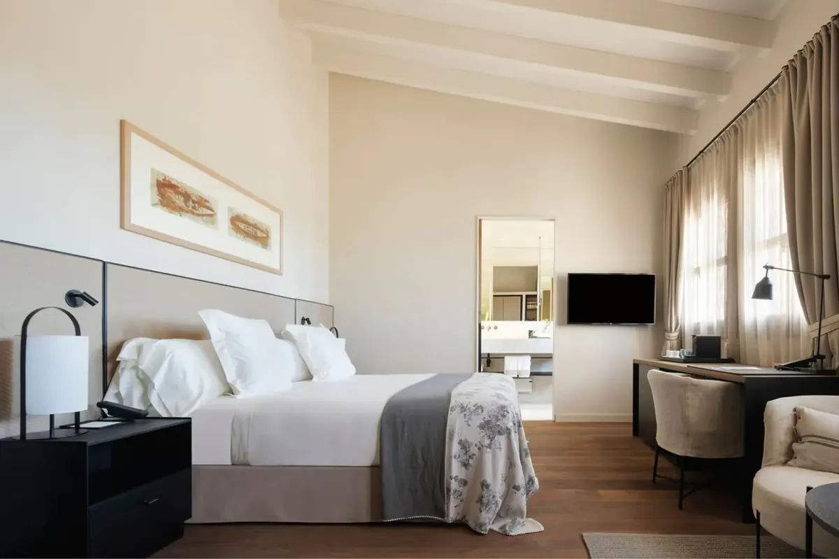 Bedroom with queen bed, wooden floors, and dual nightstands in neutral tones