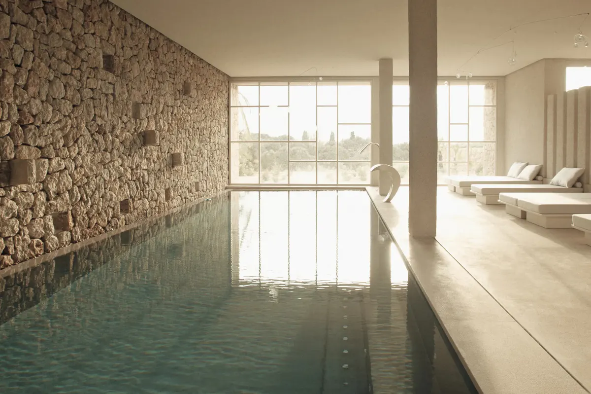 Indoor heated pool pavilion with natural stone walls and skylight illumination
