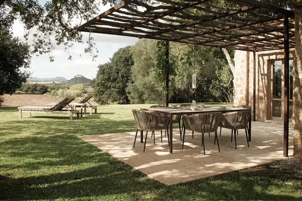 Outdoor dining pavilion with timber overhead structure, open sides, and estate grounds beyond