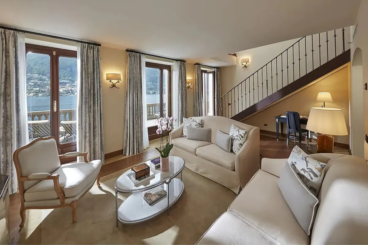 Bright bedroom with full bed, wood furnishings, and glass doors to terrace at dusk