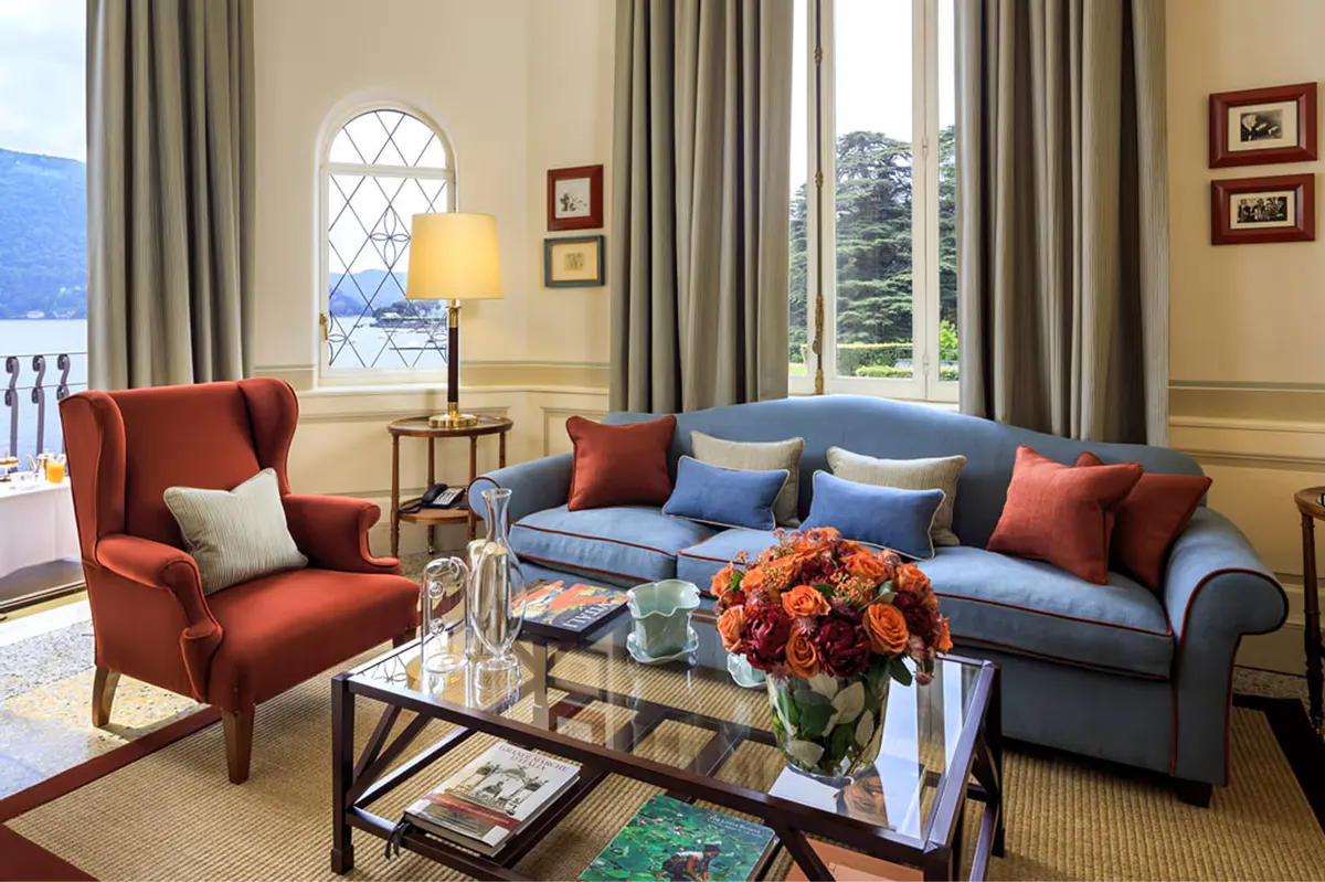 Sitting area with red armchair, decorative pillows, framed artwork, and large windows