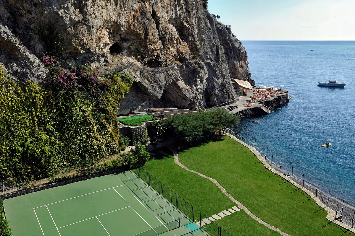 Cliffside tennis facility with views of boats, sea, and surrounding dramatic coastline