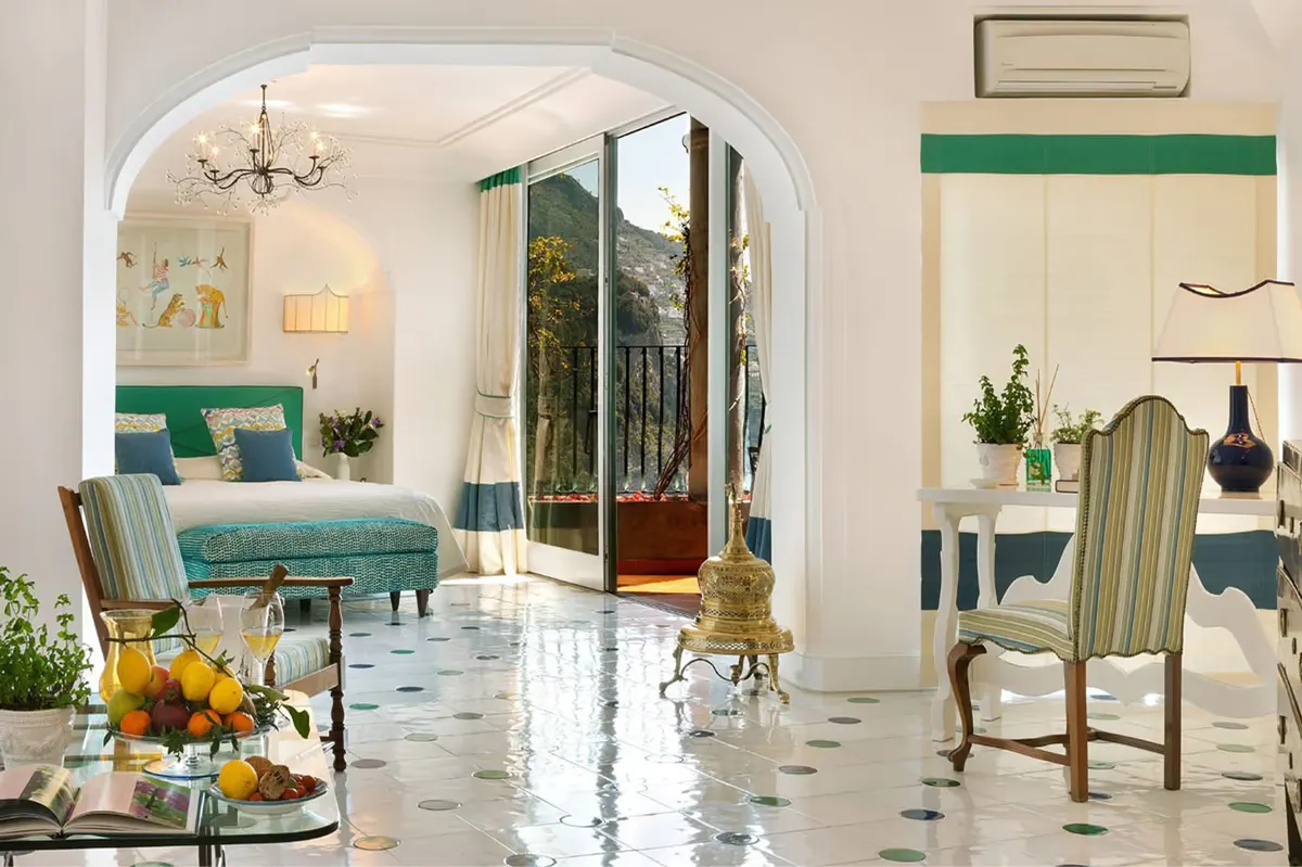Bright interior lounge with turquoise seating, arched entryway, marble flooring, and tall window