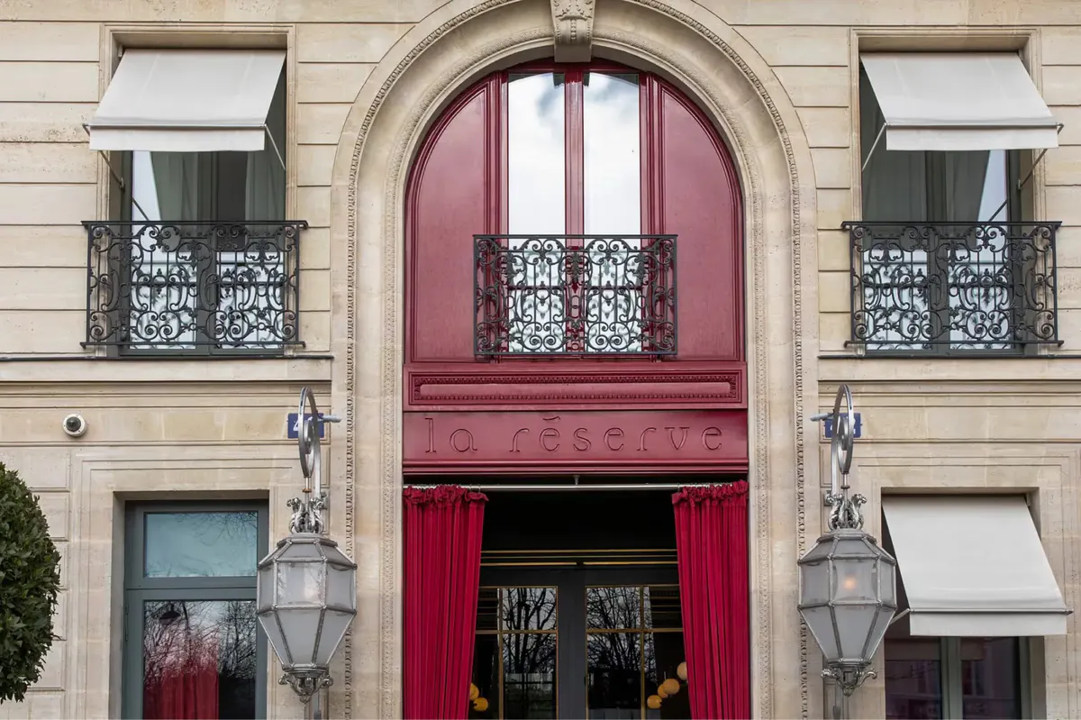 The salmon-red arched entrance with brass lanterns on either side