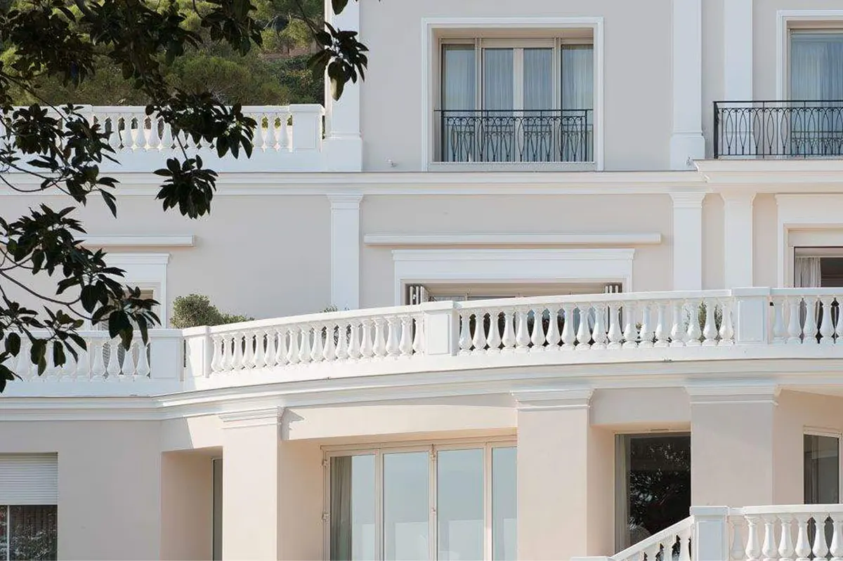 A white neoclassical facade with arched windows and stone balconies