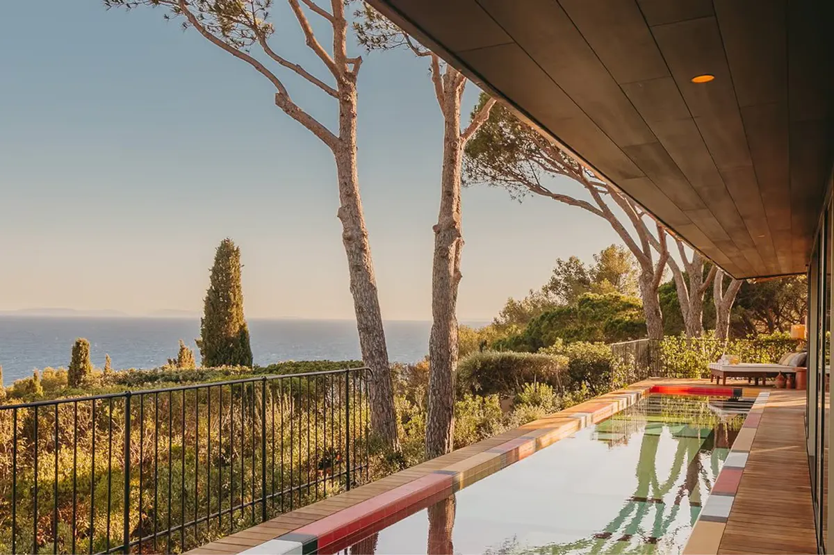 Wooden terrace beneath pine trees with Mediterranean sea view at dawn