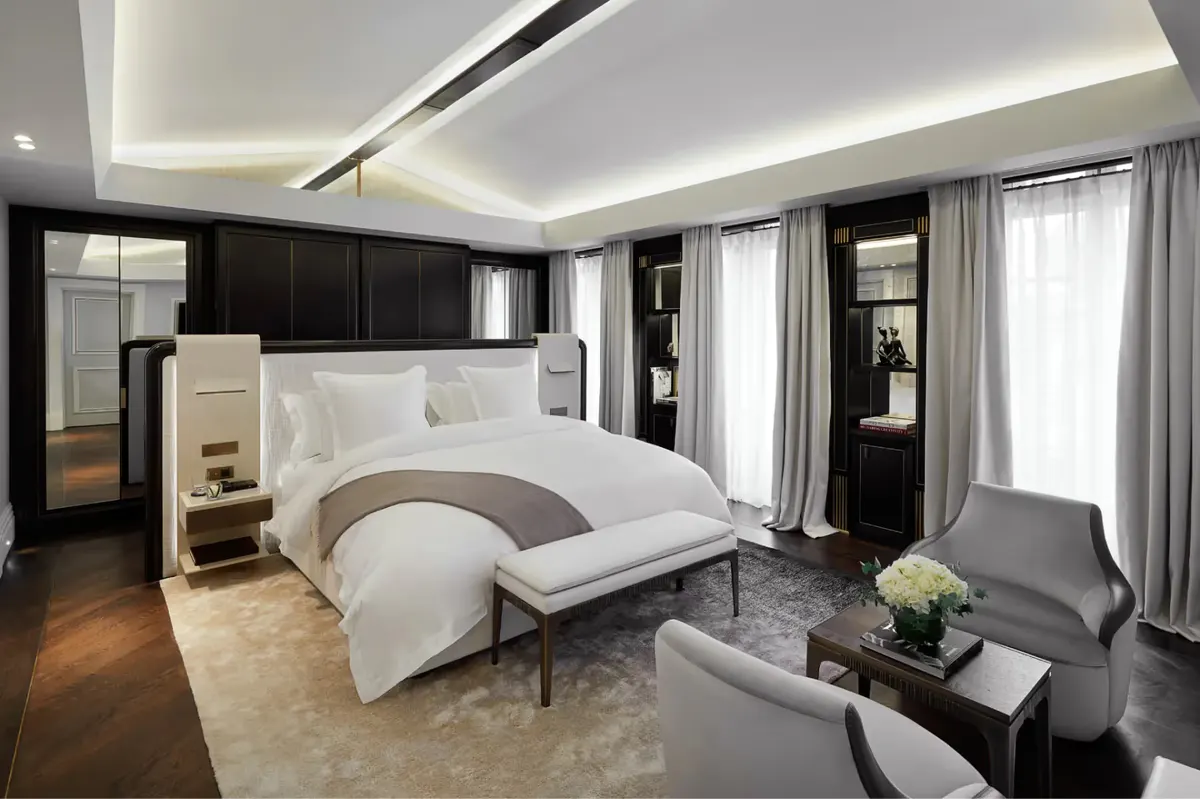 A bedroom with black and white color scheme, modern ceiling lights, pale furnishings, and sheer window drapes