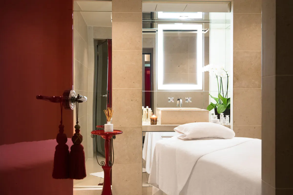 A spa treatment room with deep red accents and a massage table with white linens