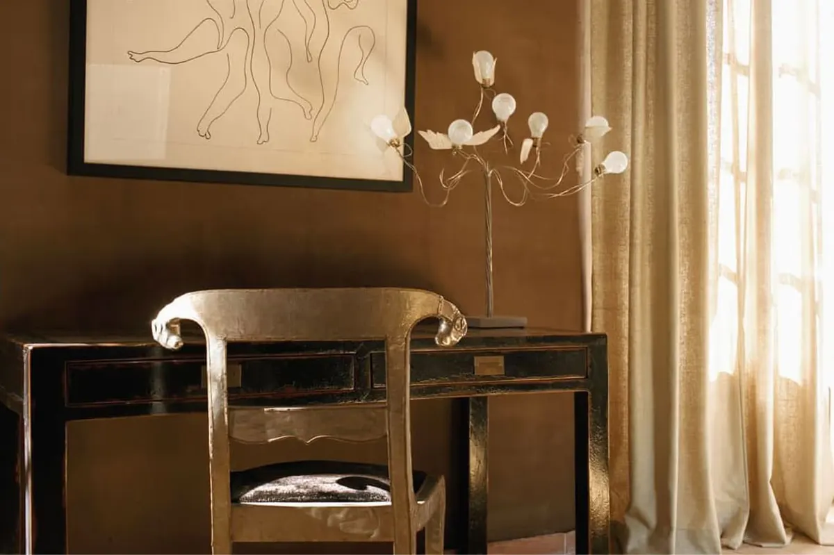 Dressing table with curved mirror, white flowers in vase, and framed line drawing