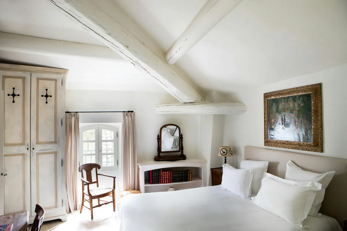 Bedroom under sloped ceiling with exposed beams and fireplace
