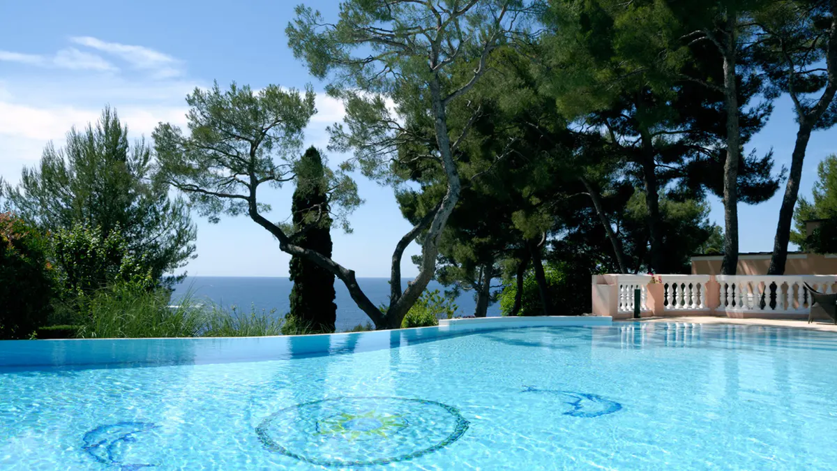 Pool beneath ancient trees with sea view and manicured grounds