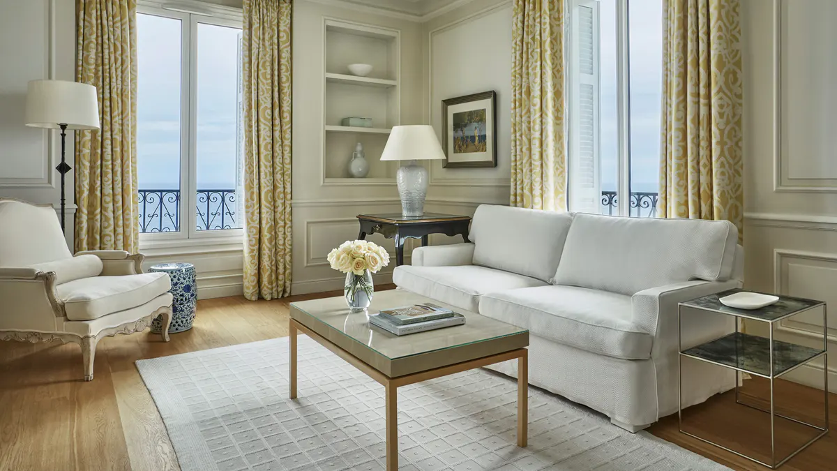 Cream parlor with gold curtains, upholstered seating, and sea-view doors