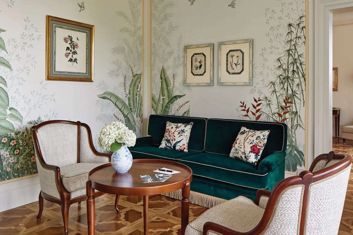 A living room with green sofa, botanical décor, and glass doors opening to terrace
