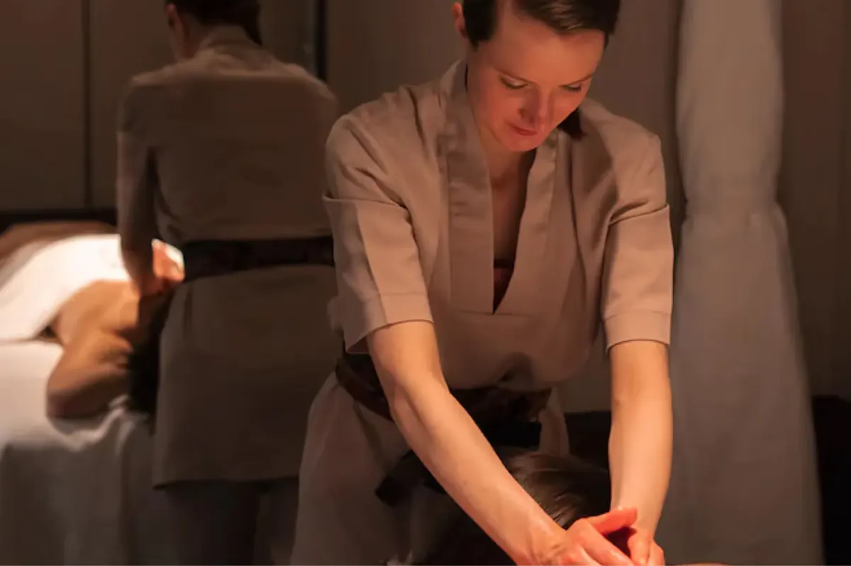 A therapist with hands on a client’s back during treatment