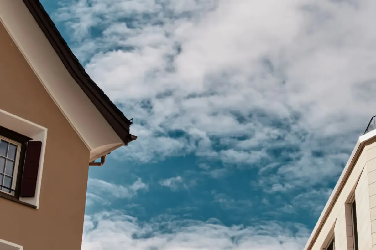 Blue sky framed by cream-colored building walls between stone structures