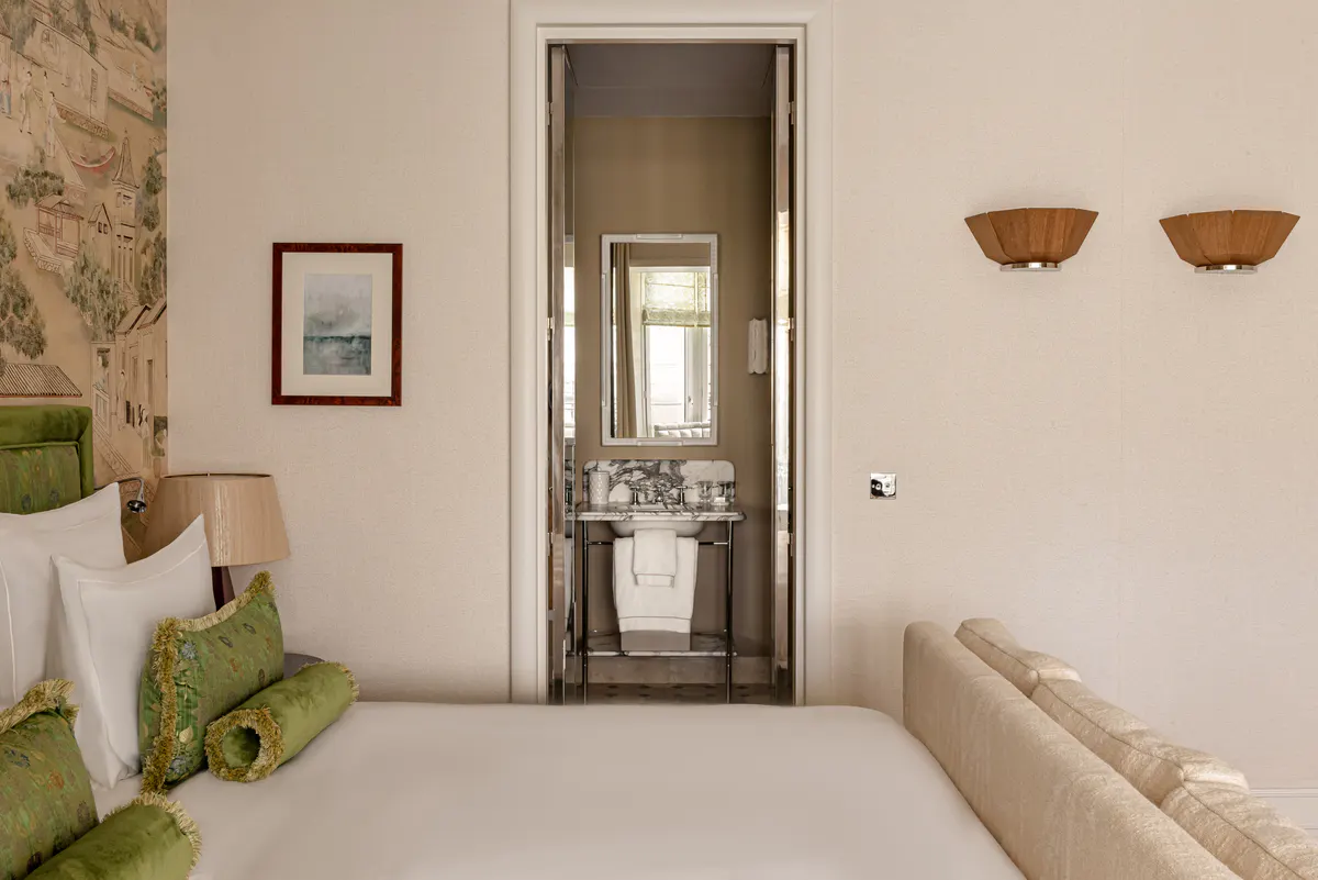 Suite interior with vintage furniture, wall-mounted mirror above desk, and garden access