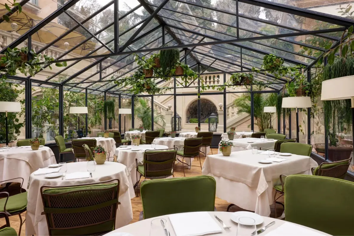 Glass conservatory dining room with arched ceilings and cream table settings